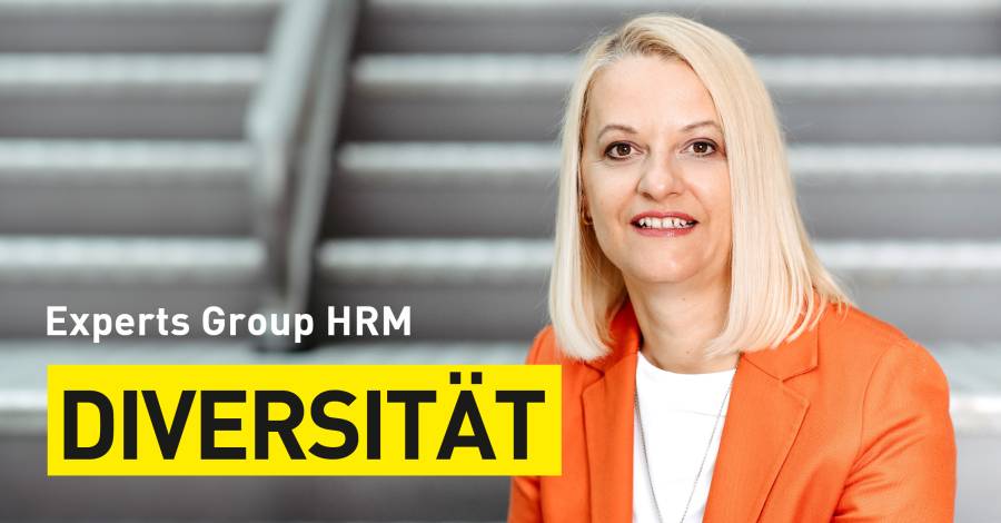 Lächelnde Person in orangefarbenem Blazer, Text „Diversität“